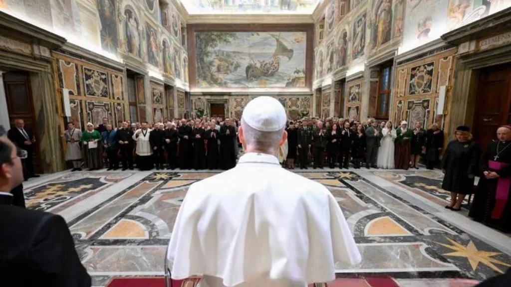Imagem papa leao xiv de costas na sala do consistorio aos presentes em 2025 do artigo Papa atualiza norma sobre presidência no Vaticano