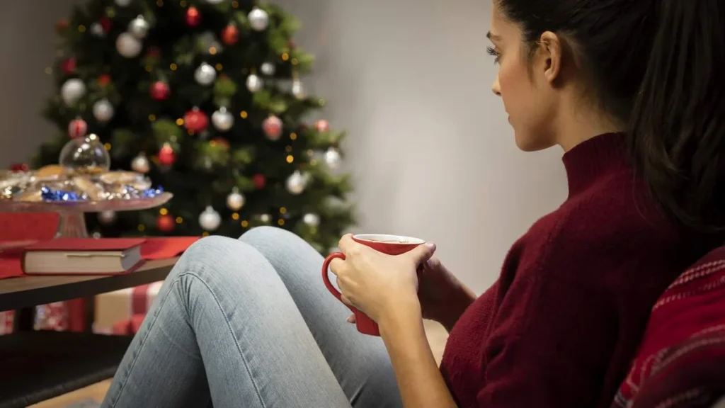 Imagem Mulher olhando para a arvore de natal e lembrando de momentos e pessoas do artigo Acolhendo a saudade: quando o Natal desperta lembranças