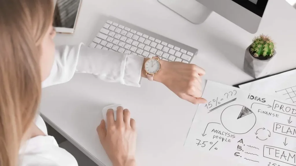 Imagem mulher conferindo o relogio durante o trabalho com outras ocupacoes na frente do artigo Aprenda como usar melhor o tempo no dia a dia com esse livro!