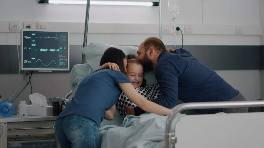 Imagem crianca no hospital sendo abracada pelos pais do artigo Visitar os enfermos: um gesto cristão de misericórdia