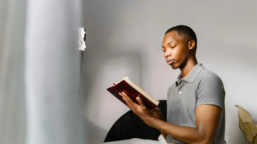 Imagem homem estudando na cama lendo a biblia do artigo Por que é um risco improvisar nos encontros de catequese?