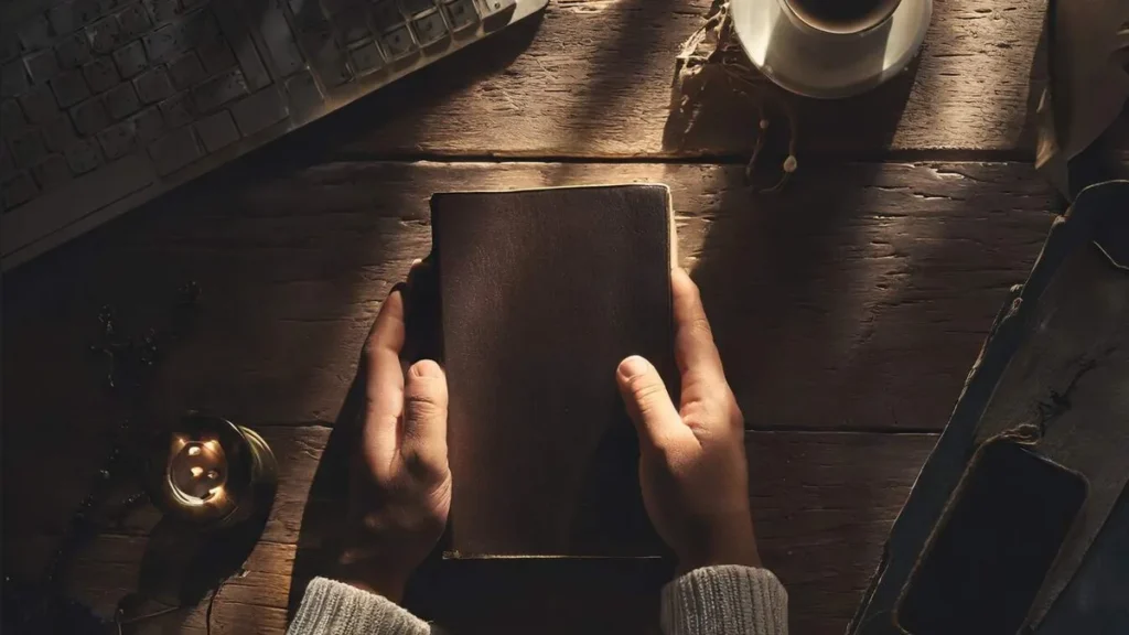Imagem pessoa segurando a biblia e rezando com um cafe e celular enquanto o sol nasce do artigo Existe horário certo para fazer minhas orações na Quaresma?