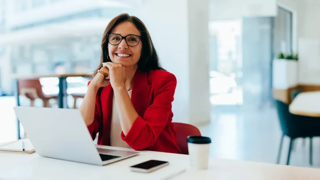 Imagem mulher sorrindo na mesa de trabalho do artigo Livro reflete sobre desafios da mulher executiva