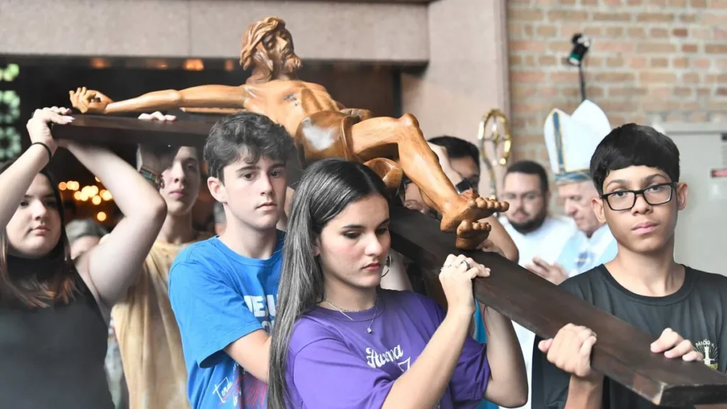 Imagem jovens segurando uma cruz em procissao do artigo Como o jovem é chamado a ocupar seu lugar na Igreja?