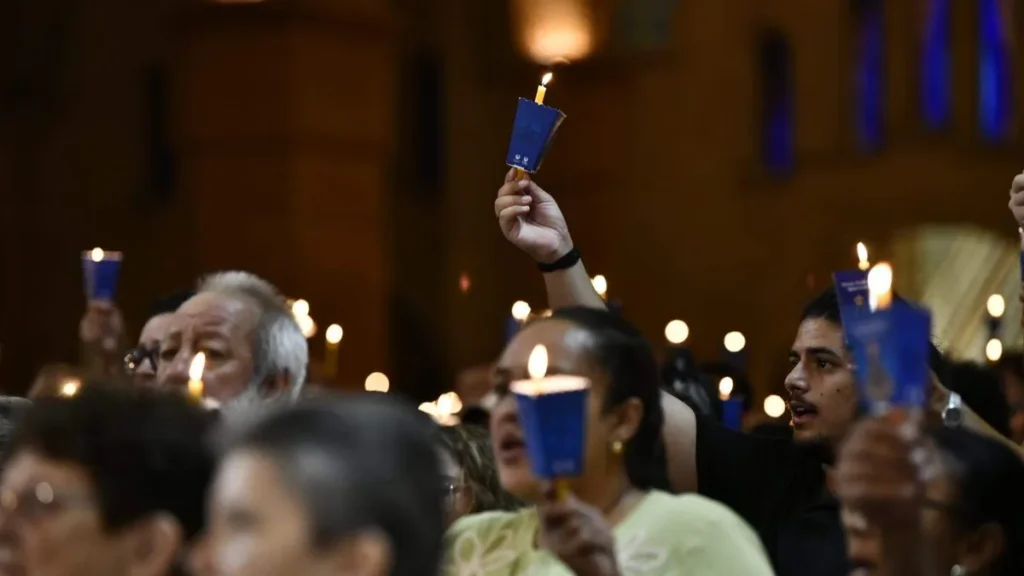 Imagem devotos com vela acesa durante vigilia pascal um devoto se sobressai com o braco mais alto em 2026 do artigo Vigília Pascal nos faz testemunhas da Ressurreição