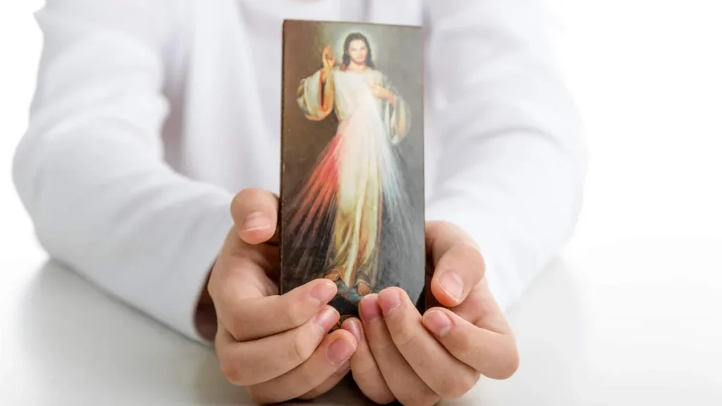 Imagem pessoa segura quadrinho de jesus misericordioso do artigo Por que celebrar o Domingo da Misericórdia?