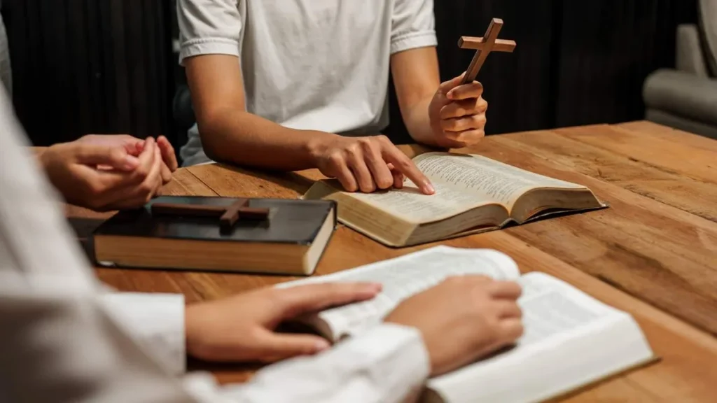 Imagem Uma mao segurando o crucifixo e outras maos em estudo do artigo Como ser uma liderança pastoral facilitadora?