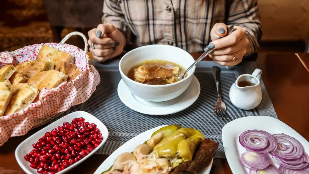 Imagem Mulher comendo em uma mesa farta de comida do artigo Por que comemos mais no outono e inverno?