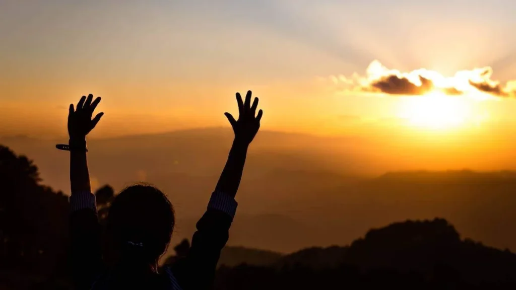Imagem pessoa com as maos para o alto e por do sol ao fundo do artigo Deus pode perdoar um pecado mortal?
